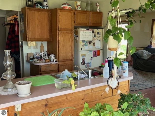 394 Wilson Ave, Mount Morris, MI 48458 - kitchen with freestanding refrigerator, light countertops, brown cabinetry, a sink, and open floor plan