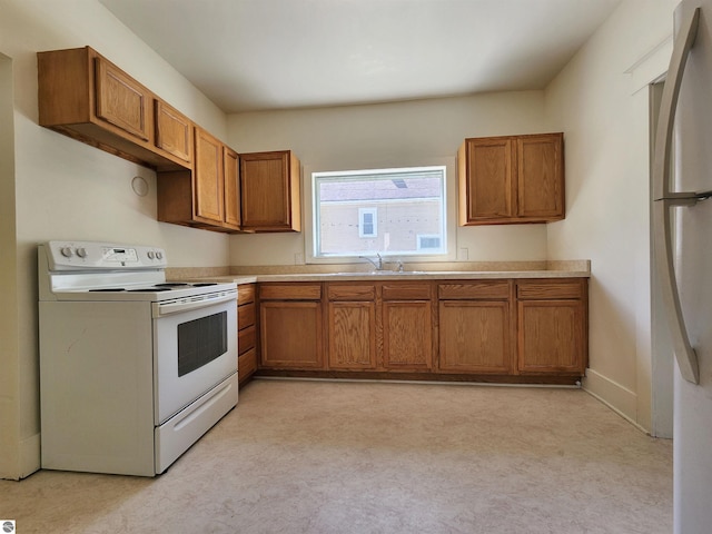 kitchen with white appliances, brown cabinetry, and a sink