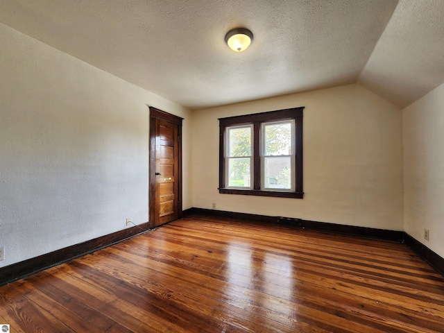 additional living space featuring hardwood / wood-style floors, a textured ceiling, lofted ceiling, and baseboards