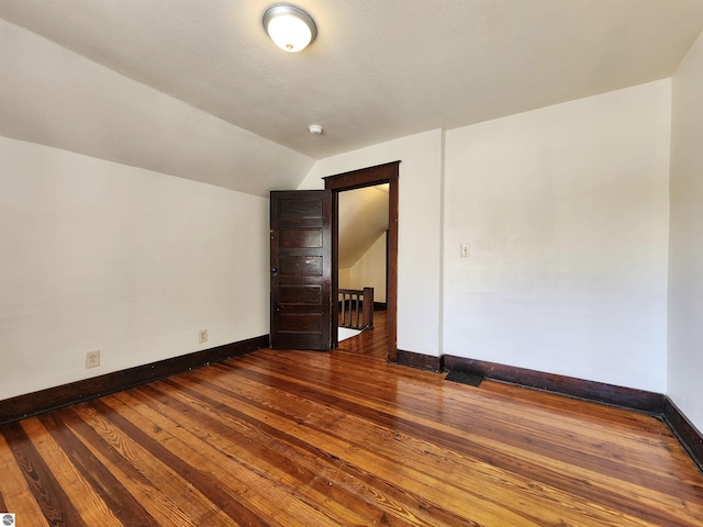 unfurnished room with baseboards, lofted ceiling, and hardwood / wood-style flooring