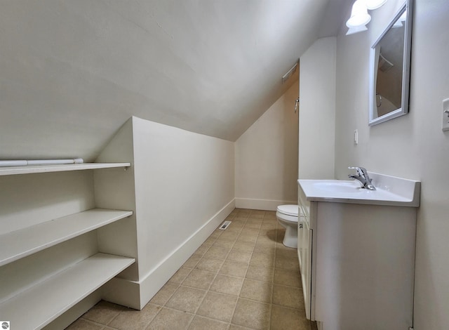 bathroom with lofted ceiling, toilet, vanity, tile patterned floors, and baseboards