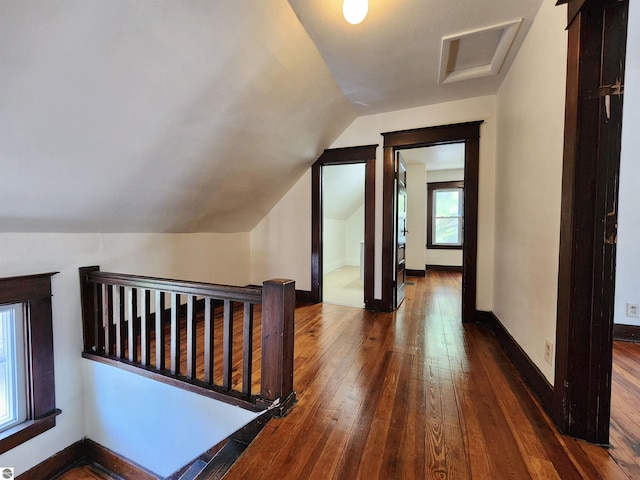 corridor with hardwood / wood-style flooring, lofted ceiling, an upstairs landing, attic access, and baseboards