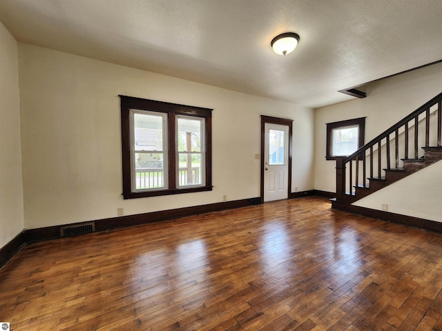 foyer entrance featuring hardwood / wood-style floors, stairway, baseboards, and a textured ceiling
