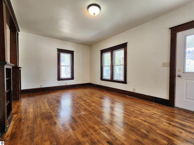 unfurnished living room with hardwood / wood-style floors, plenty of natural light, and baseboards
