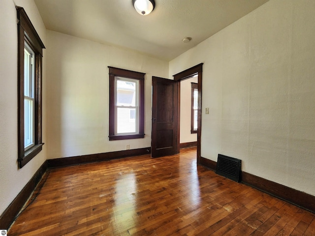spare room featuring wood-type flooring and baseboards