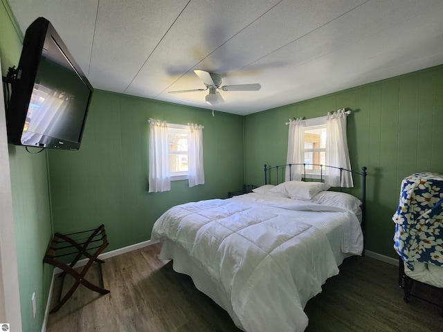 bedroom with wood finished floors, multiple windows, baseboards, ceiling fan, and a textured ceiling