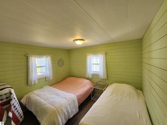 bedroom with wooden walls, dark wood-type flooring, and a textured ceiling