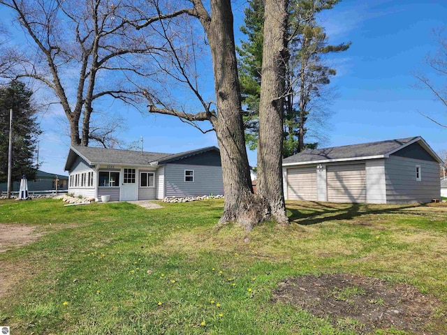 view of grassy yard featuring a detached garage and an outbuilding