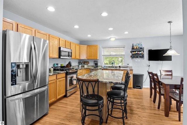 8565 Bent Pine Dr, Lake Ann, MI 49650 - kitchen with appliances with stainless steel finishes, light wood-style flooring, recessed lighting, a kitchen island, and a breakfast bar