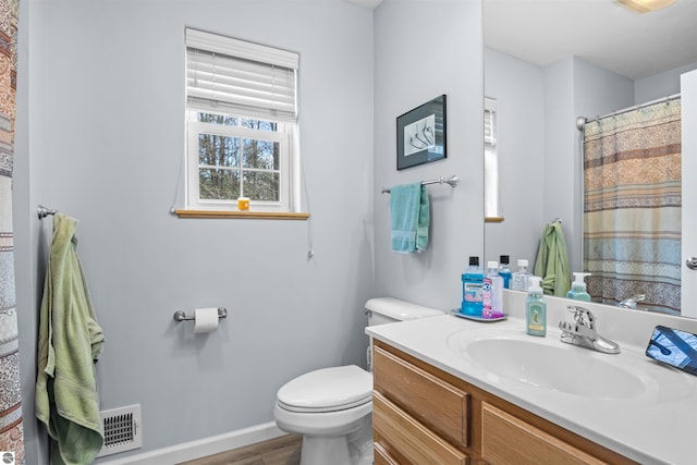 8565 Bent Pine Dr, Lake Ann, MI 49650 - bathroom with toilet, wood finished floors, vanity, baseboards, and a shower with curtain