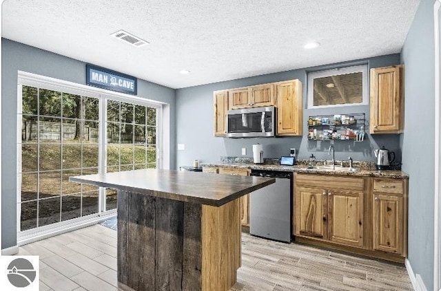 8565 Bent Pine Dr, Lake Ann, MI 49650 - kitchen featuring appliances with stainless steel finishes, a sink, light wood finished floors, a textured ceiling, and dark countertops
