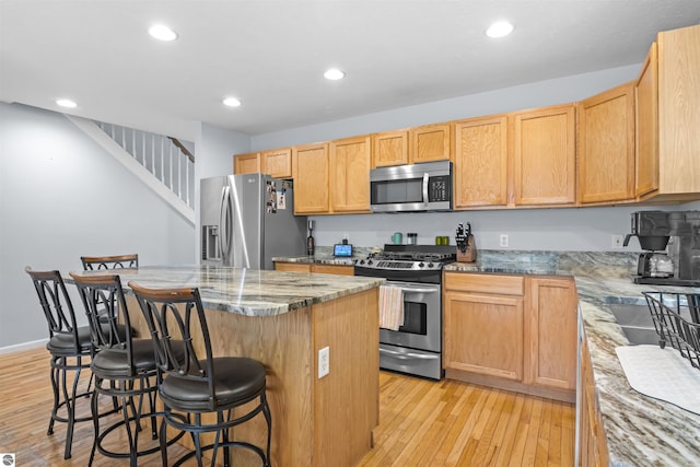 8565 Bent Pine Dr, Lake Ann, MI 49650 - kitchen with stainless steel appliances, a breakfast bar, a kitchen island, light wood-style flooring, and recessed lighting