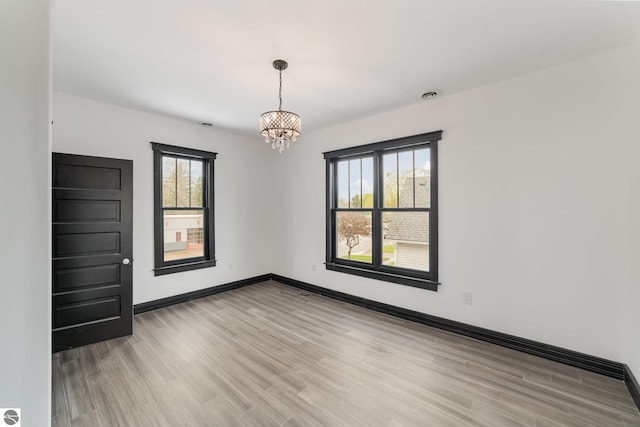 117 S Fancher St, Mount Pleasant, MI 48858 - unfurnished room with a chandelier, light wood-type flooring, and baseboards