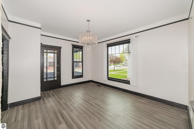 117 S Fancher St, Mount Pleasant, MI 48858 - empty room featuring wood finished floors, a chandelier, baseboards, and healthy amount of natural light