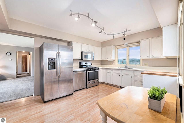4120 M-66, Kalkaska, MI 49646 - kitchen with stainless steel appliances, a sink, light countertops, white cabinetry, and light wood finished floors