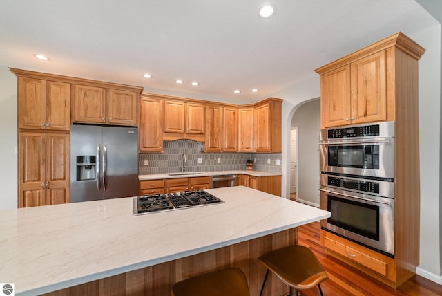 726 Doe Trl, Mount Pleasant, MI 48858 - kitchen with stainless steel appliances, arched walkways, recessed lighting, backsplash, and light stone countertops