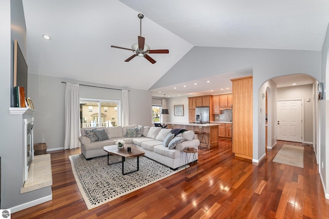 726 Doe Trl, Mount Pleasant, MI 48858 - living area with arched walkways, ceiling fan, high vaulted ceiling, wood finished floors, and a fireplace with raised hearth