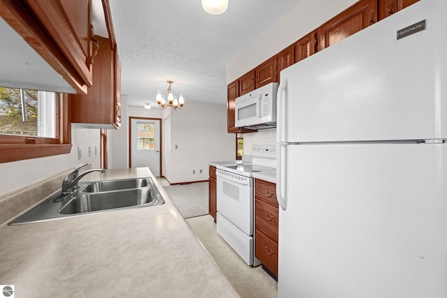 203 W Sixteenth St, Traverse City, MI 49684 - kitchen featuring white appliances, a sink, a chandelier, light countertops, and hanging light fixtures