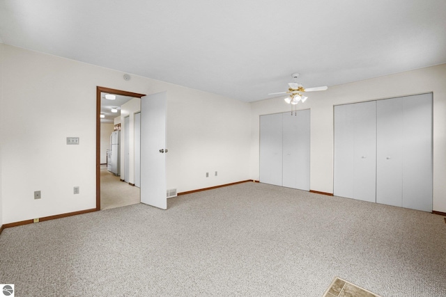 203 W Sixteenth St, Traverse City, MI 49684 - unfurnished bedroom featuring multiple closets, light carpet, baseboards, a ceiling fan, and freestanding refrigerator