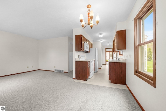 203 W Sixteenth St, Traverse City, MI 49684 - kitchen with white appliances, a chandelier, light countertops, and light colored carpet
