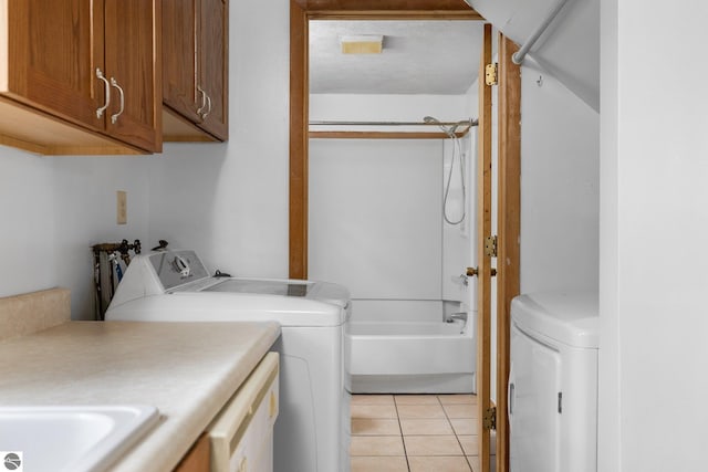 laundry area with cabinet space, washer and clothes dryer, and light tile patterned floors