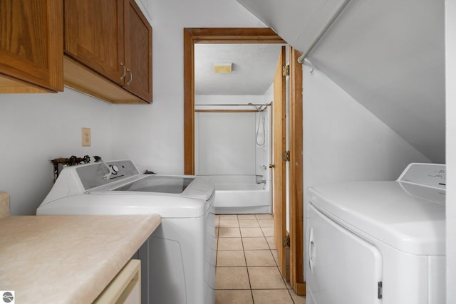 clothes washing area featuring independent washer and dryer, cabinet space, and light tile patterned floors