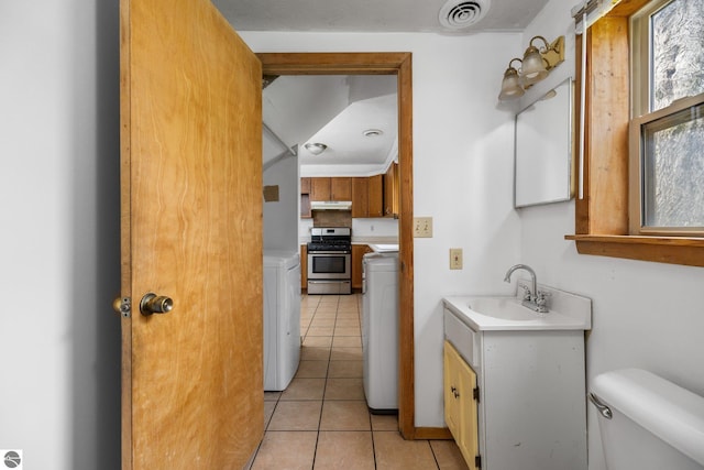 half bath with toilet, tile patterned flooring, washer and dryer, and vanity