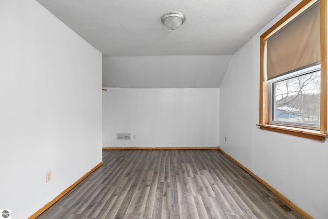 additional living space with baseboards, vaulted ceiling, and wood finished floors