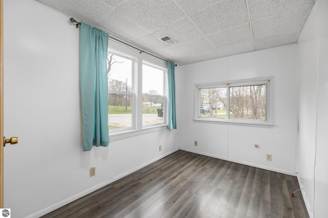 unfurnished room featuring dark wood-style floors, baseboards, and a drop ceiling