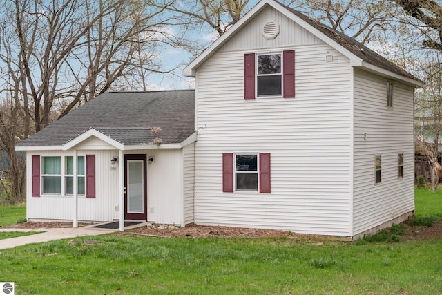 traditional-style house featuring a shingled roof and a front yard