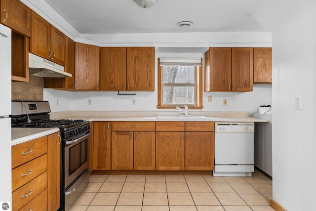 kitchen featuring dishwasher, stainless steel range with gas cooktop, under cabinet range hood, light countertops, and brown cabinets