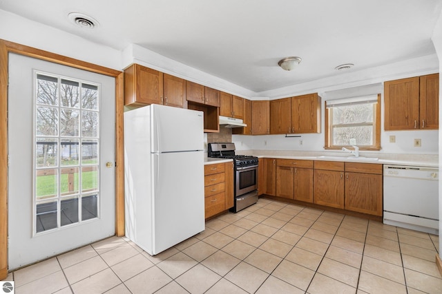 kitchen featuring white appliances, a sink, light countertops, and healthy amount of natural light