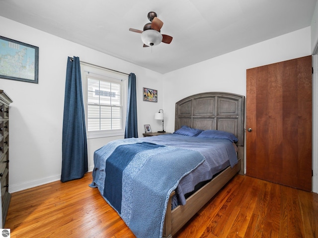 bedroom with wood finished floors, baseboards, and a ceiling fan