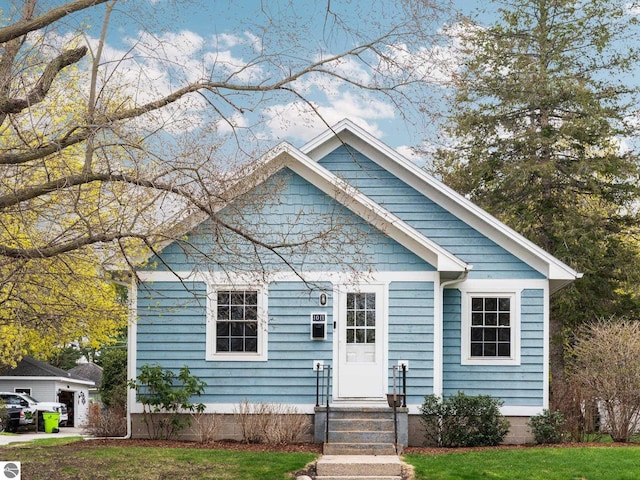 bungalow-style home with entry steps and a front yard