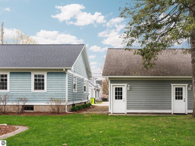 back of property with a yard and roof with shingles