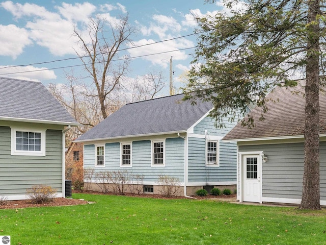 back of property with a lawn and a shingled roof