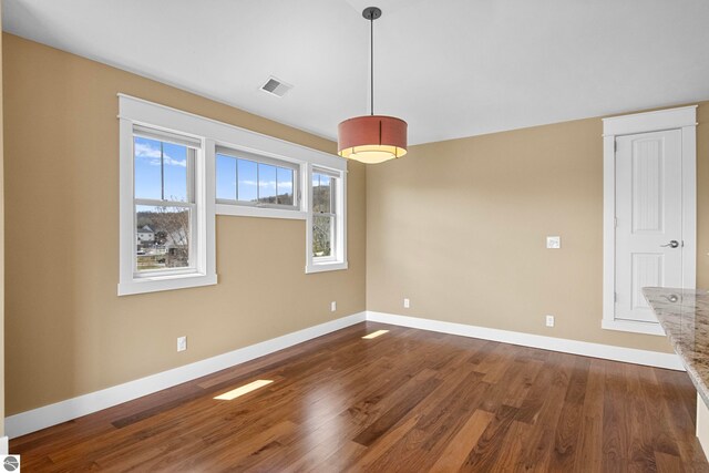 10889 Pine Bluff Dr Unit C, Traverse City, MI 49684 - unfurnished dining area featuring dark wood-type flooring and baseboards