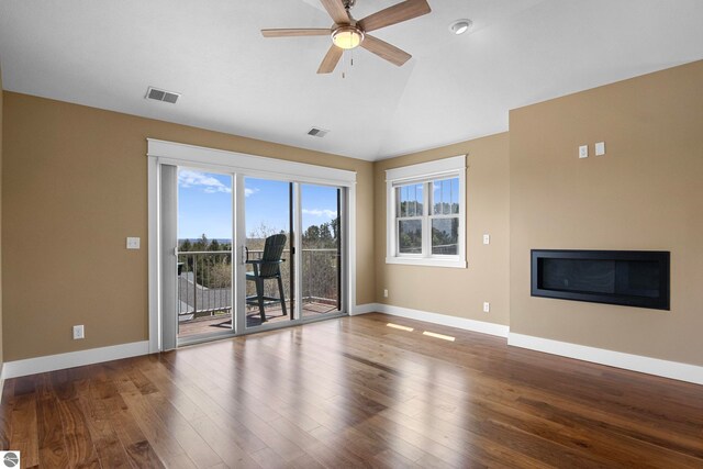 10889 Pine Bluff Dr Unit C, Traverse City, MI 49684 - unfurnished living room featuring a glass covered fireplace, lofted ceiling, wood finished floors, a ceiling fan, and baseboards