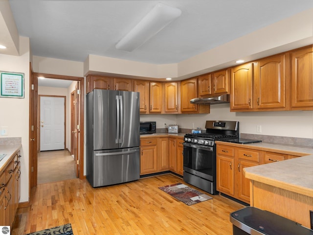 4381 Cherry Ln, Traverse City, MI 49684 - kitchen featuring appliances with stainless steel finishes, under cabinet range hood, light wood-style flooring, recessed lighting, and light countertops