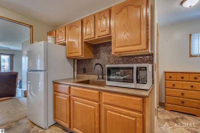 kitchen featuring white appliances, a sink, decorative backsplash, and stone finish flooring