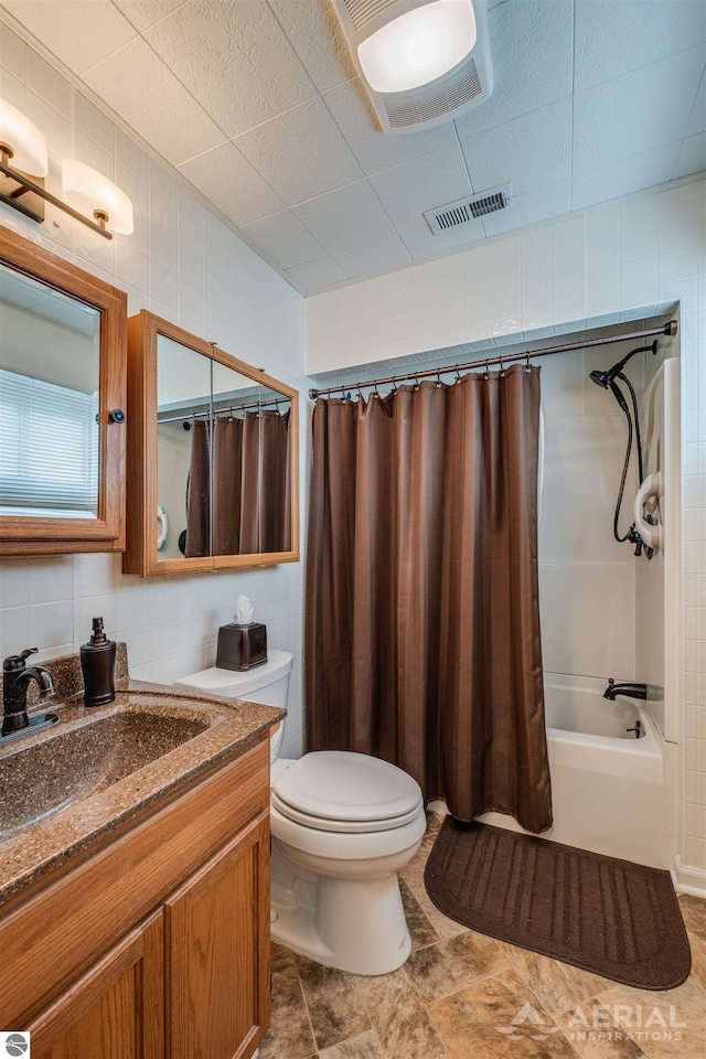 full bath featuring tile walls, toilet, vanity, and shower / bathtub combination with curtain