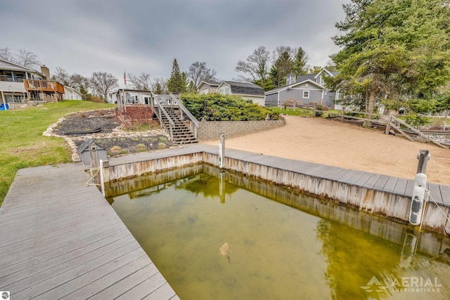 dock area featuring a residential view, stairway, a yard, and a water view