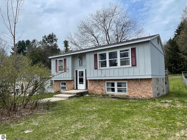 1993 W St, Central Lake, MI 49622 - split foyer home with board and batten siding, a front yard, and brick siding