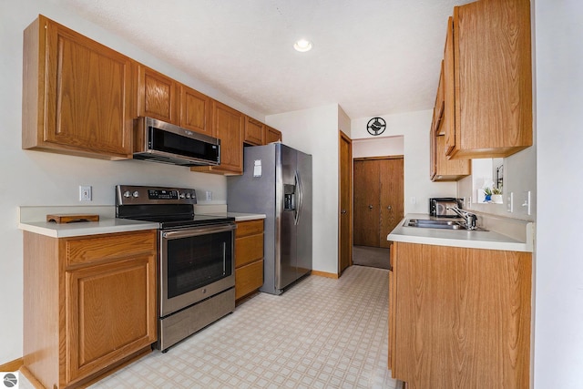 3691 Eastview Dr Unit 67, Traverse City, MI 49684 - kitchen with stainless steel appliances, a sink, light flooring, light countertops, and brown cabinetry