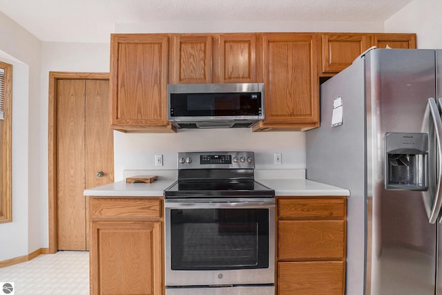 3691 Eastview Dr Unit 67, Traverse City, MI 49684 - kitchen featuring appliances with stainless steel finishes, light countertops, light flooring, and brown cabinets