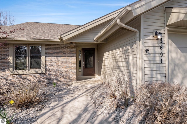 3691 Eastview Dr Unit 67, Traverse City, MI 49684 - entrance to property featuring brick siding, roof with shingles, and an attached garage