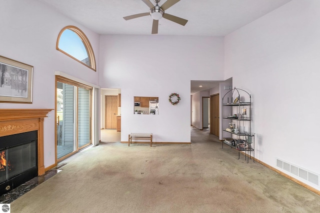3691 Eastview Dr Unit 67, Traverse City, MI 49684 - unfurnished living room featuring a towering ceiling, ceiling fan, a fireplace with flush hearth, carpet floors, and baseboards