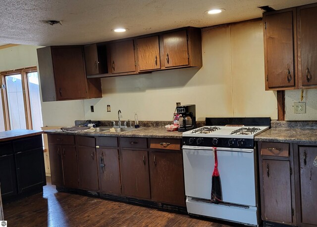 21187 Parkview Rd, Tustin, MI 49688 - kitchen featuring gas range gas stove, dark countertops, a sink, dark wood-style floors, and dark brown cabinets