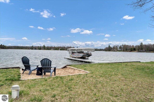 dock featuring a water view, a lawn, and boat lift