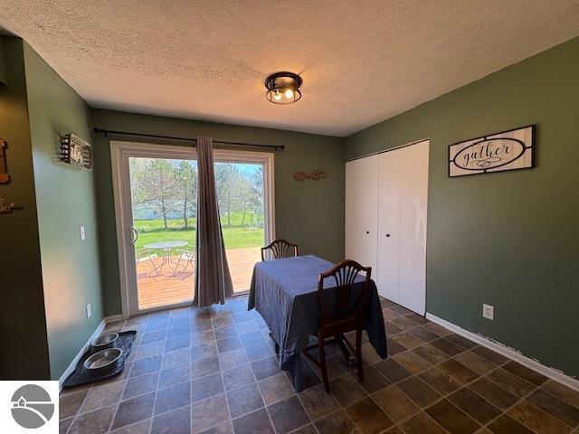 2195 S Sara Dr, Lake City, MI 49651 - dining room featuring a textured ceiling and baseboards